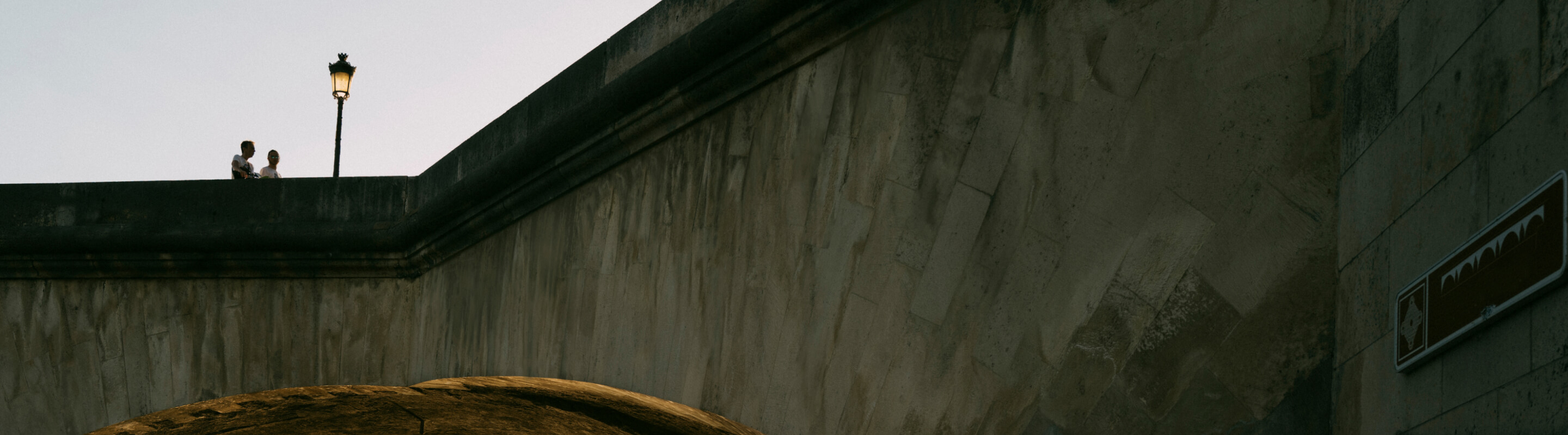 A wide shot of two people walking across an bridge overpass